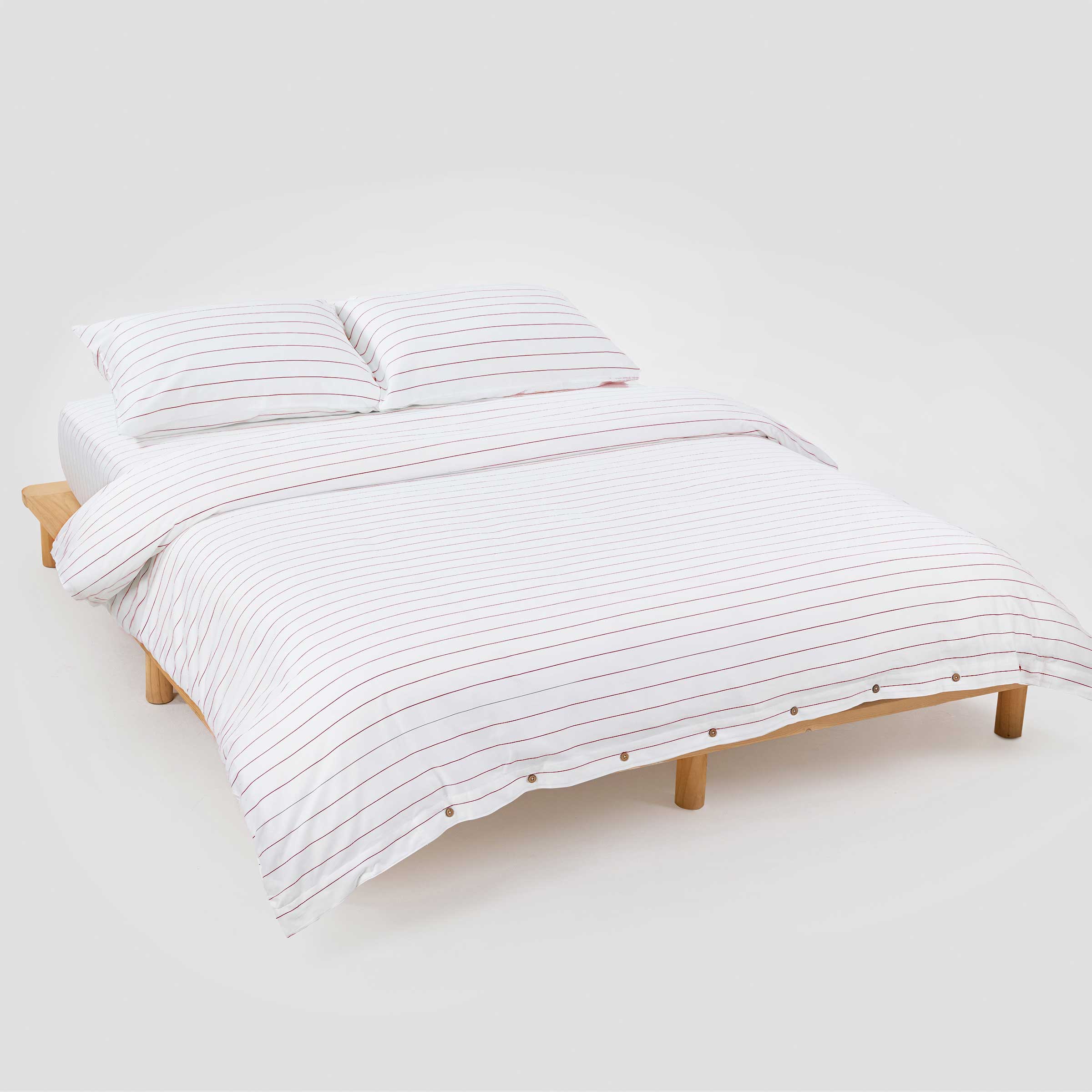 Bed with white striped bedding on a plain background