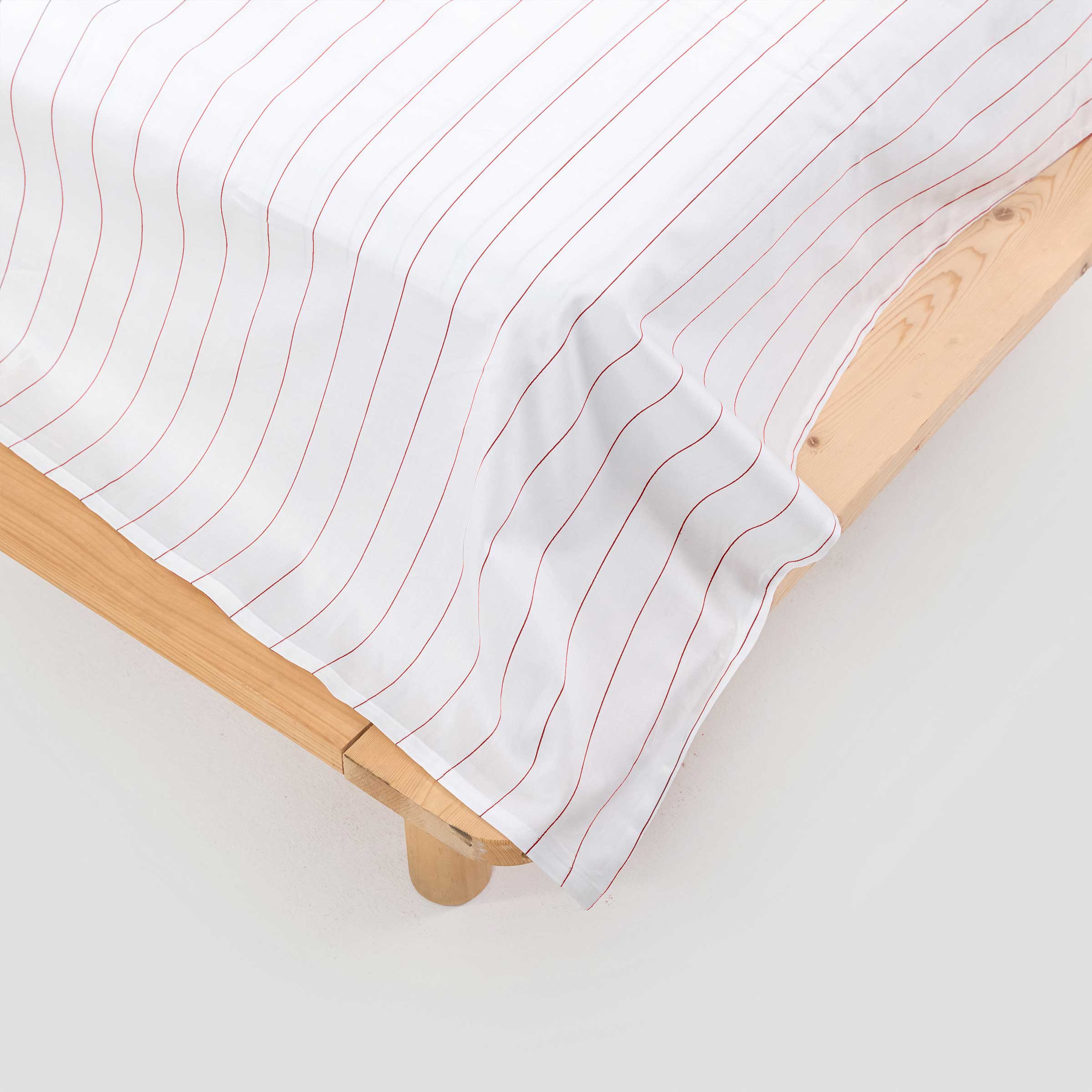 White fitted sheet with red lines on a wooden bed frame.