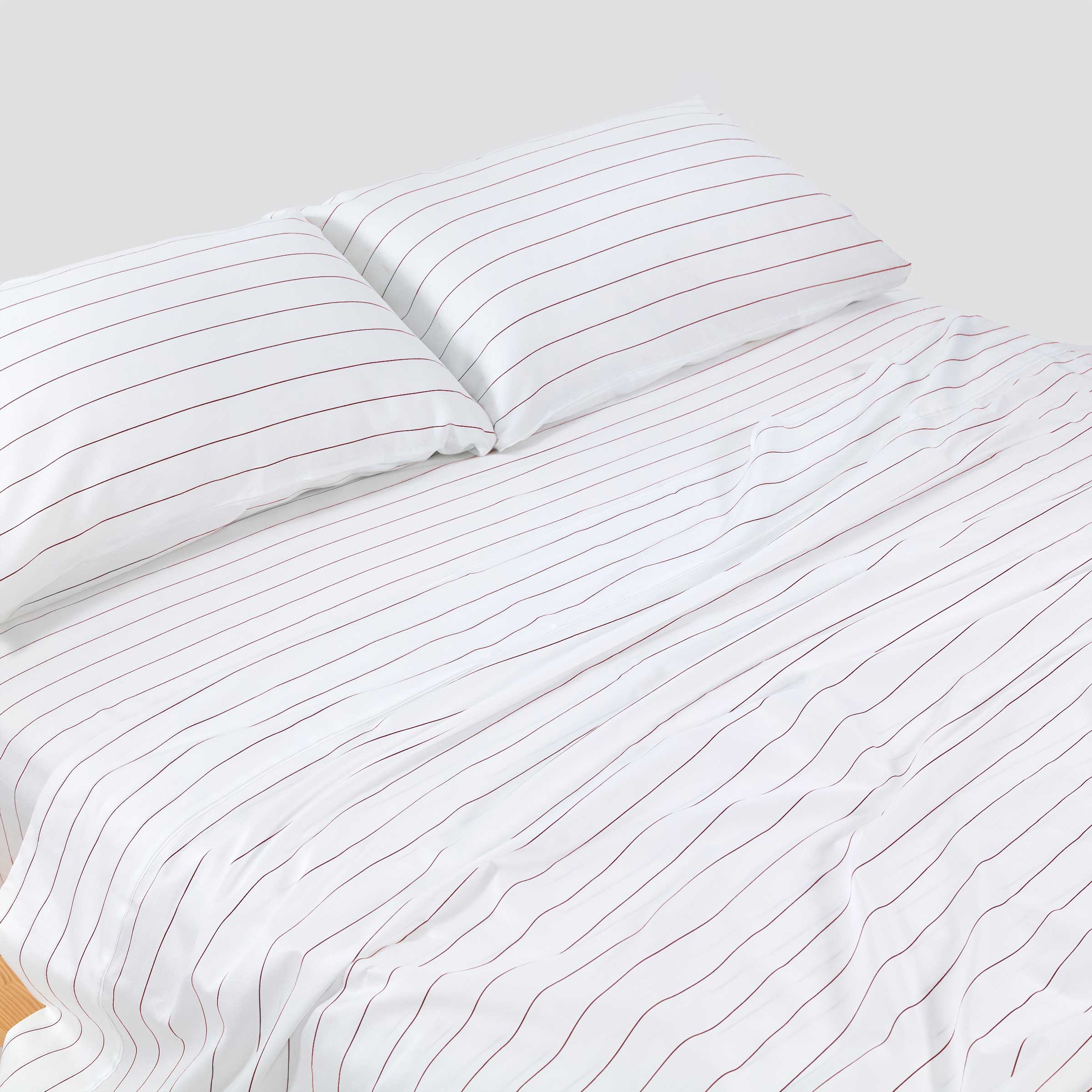 White striped bedding set on a bed with a plain background